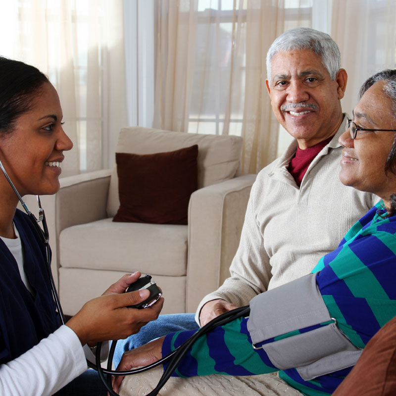 In-home nurse talking with and elderly woman and her husband